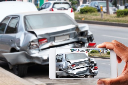 a phone screen taking a picture of a car that was damaged in a car accident