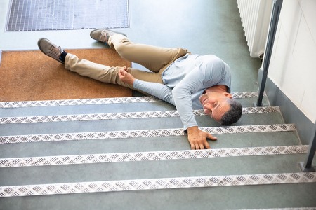 Man in pain laying on stairs after a slip and fall accident